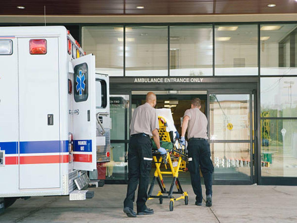 Emergency responders wheel a patient out of an ambulance and into an ER