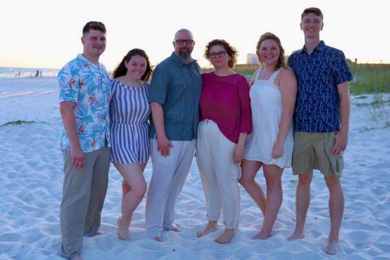 A group of five people posing on a beach at dusk