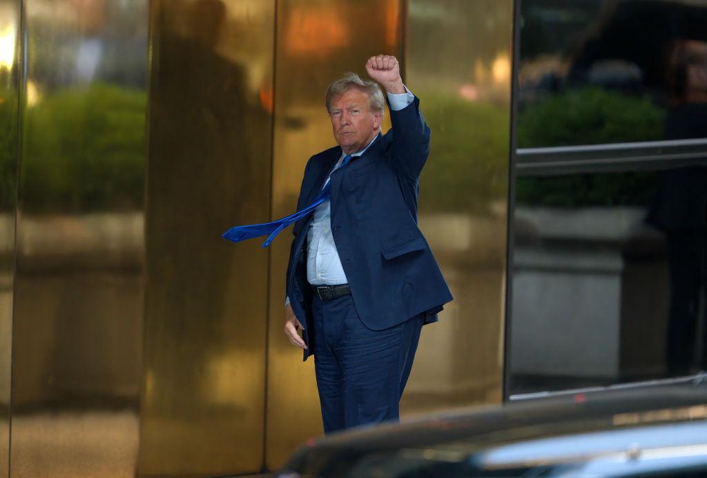 Donald Trump arrives at Trump Tower after the first day of his trial with his hand held high